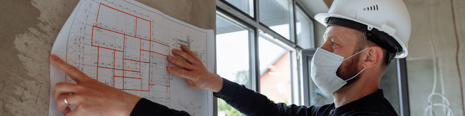 contractor holding floor plan against unfinished wall